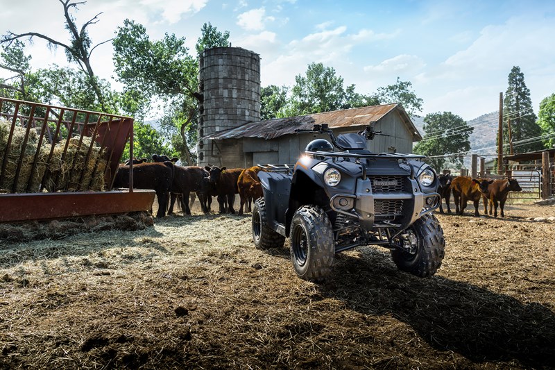 A young kid riding a Yamaha Grizzly 90 in the forest with trees in the background